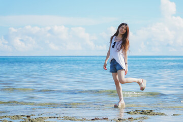 Fototapeta na wymiar 石垣島の海の波打ち際を歩く女性