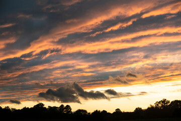 Stunning Summer sunset sky with colorful vibrant clouds and sun beams across whole sky