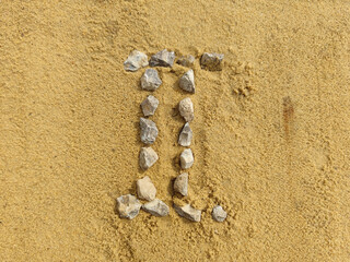 the Roman numeral 2 is laid out with stones on the river sand.