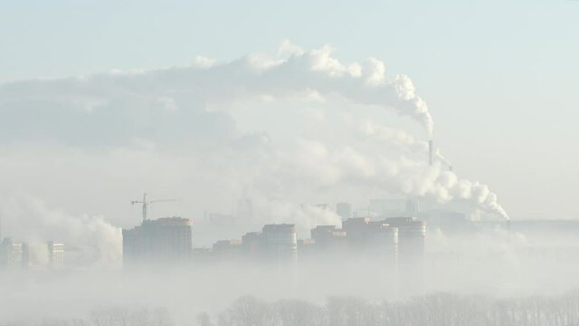 Smoke comes out of several pipes over the high buildings, Novosibirsk city, Russia