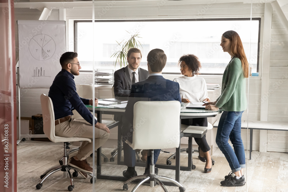 Wall mural multiethnic employees gather at desk in boardroom talk brainstorm at meeting together, concentrated 