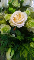 Flower background of bouquet of yellow, white and cream shade roses. Green leaves. Beauty in nature. Summer inspiration. Cut flowers. Love concept of aesthetics. Floristic decor. Rose vertical card.

