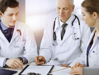 Doctors colleagues and elderly therapist discussing current disease therapy while sitting at...