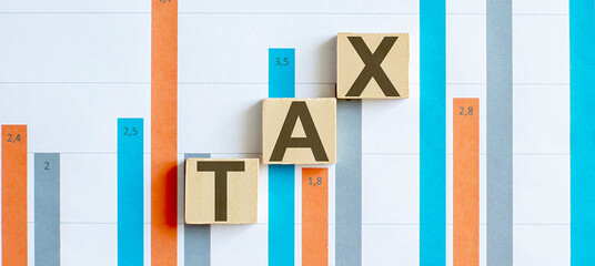 TAX word letters on wooden blocks on chart background. BUSINESS concept.