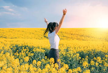 Modern young woman turned away, prays, raised hands up. Brunette girl enjoy beauty spring divine...