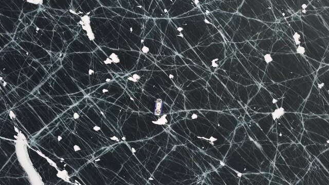 Aerial view of the machine moving on the frozen amazing lake. Clip. Typical hovercraft vehicle on clear craked ice surface, Lake Baikal, Siberia, Russia.