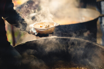cook scoops up food from a cauldron