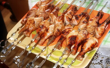 Charcoal-fried chicken legs strung on a skewer on a tray