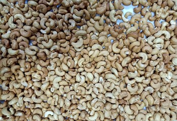 Many cashews are snacks that are laid out on white paper.