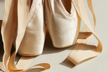 Cropped shot of point shoes. Ballet shoes,  beige colors. Pointe shoes on the floor, close-up. Abstract ballet background.