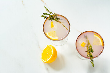 Two cocktails with ice in wine glasses, decorated with lemon slices.