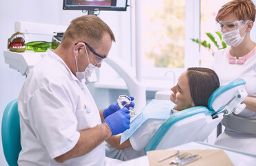 Obraz premium Doctor dentist treats teeth of a beautiful young girl patient. The girl on reception at the dentist. Doctor dentist treats tooth