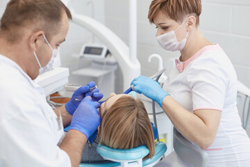 Doctor dentist treats teeth of a beautiful young girl patient. The girl on reception at the dentist. Doctor dentist treats tooth