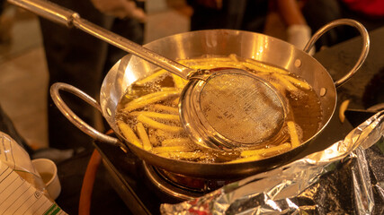 French fries frying in a large pan