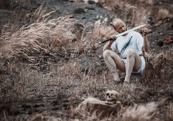 Warlike wanderer in the mountains resting after a battle with a dagger in his hand