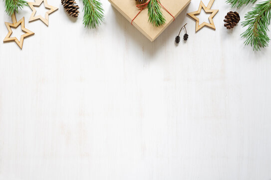 Christmas tree branches, cones and wooden Christmas accessories on a white wooden background.