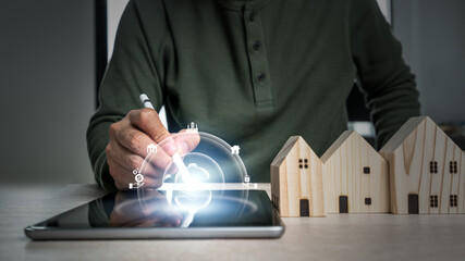 Man hand select a home model on the wood table. Loan or saving money to buy a new house in the future concept.