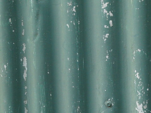 Galvanized corrugated metal wall background with chipped green paint