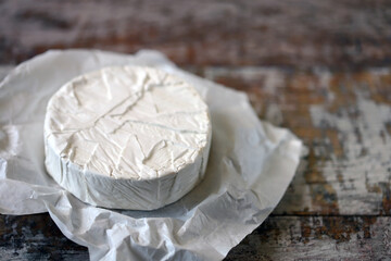 Round camembert cheese in paper.