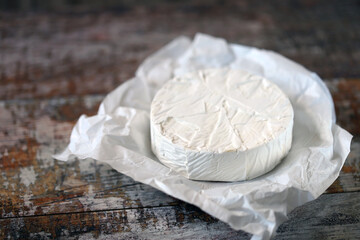 Round camembert cheese in paper.
