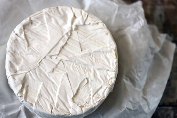 Round camembert cheese in paper.