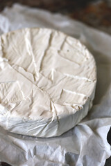 Fototapeta na wymiar Round camembert cheese in paper.
