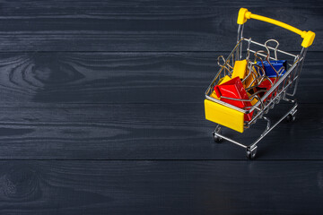 Naklejka premium Paper clips in shopping cart on a black wooden background