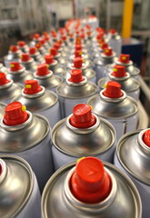 Aerosol cans with red spray buttons in manufacturing factory