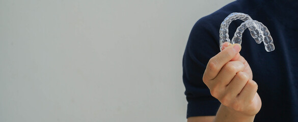 close up man hand holding dental aligner retainer (invisible) on  background for beautiful teeth treatment course concept