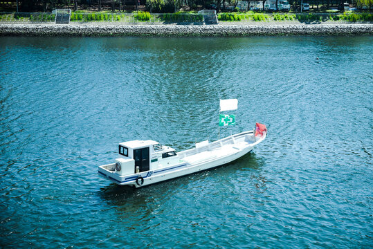 a small white boat floating on a river in Tokyo.