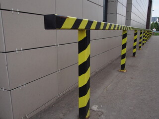 warehouse barriers and bumpers of warning black and yellow coloring, mounted along the street walls