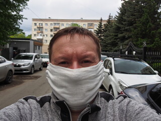 A man in a gauze mask on a city street. Close-up portrait