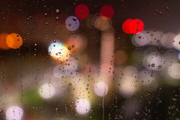 Raindrops on the window glass at night against the background of bokeh from the lights and Windows of the houses opposite