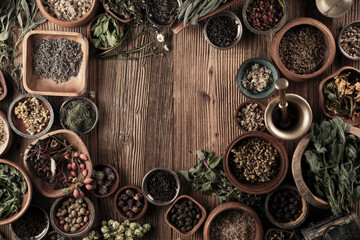 Large spice and herb collection in bowls and spoons forming an abstract background.