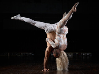 A sports couple of acrobats performs the trick. Acrobats on a dark background.