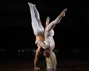 A sports couple of acrobats performs the trick. Acrobats on a dark background.