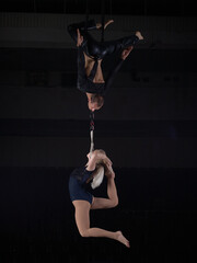 A sports acrobat couple performs a trick in the air. Acrobats on a dark background.