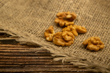 Peeled walnuts in bulk on a wooden table covered with rough-textured burlap. Healthy diet. Fitness diet. Close up.