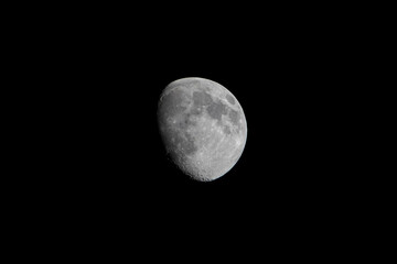 Moon in the black sky in the evening. Seen from the ground up with binoculars. close up image