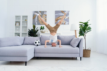Adorable child standing on his head on sofa at home stock photo