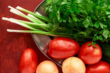 healthy food - fresh vegetables and greens on a wooden background, greens, onion and tomatoes