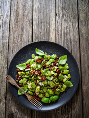 Broad beans salad with sun dried tomatoes, garlic and onion on wooden table
