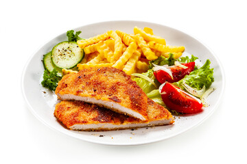 Breaded fried pork chop, French fries and vegetables on white background
