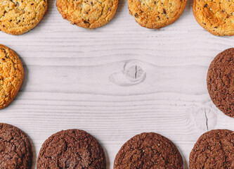Food frame, Oat and chocolate cookies on a white wooden background laid out in the form of a square frame with copy space. Image use for commercial or menu layout design. Tasty and junk food concept