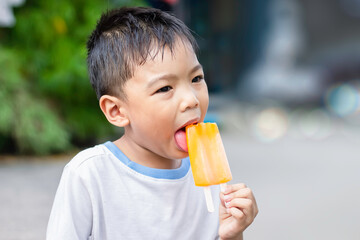 Happy Asian child boy eating an pink vanilla ice cream. Summer season, Delicious feeling, childhood sloppy face.
