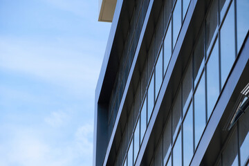 facade of a modern building on a bright Sunny day, blue sky and clouds reflecting in a glass, beautiful exterior of the new building