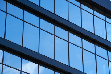 facade of a modern building on a bright Sunny day, blue sky and clouds reflecting in a glass, beautiful exterior of the new building