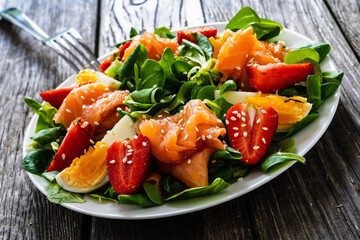 Salmon salad - smoked salmon boiled egg and vegetables on wooden background
