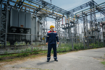 An electrical substation engineer inspects modern high-voltage equipment in a protective mask . Energy. Industry