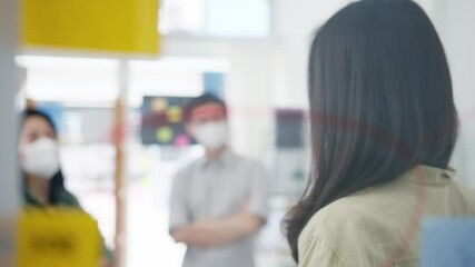 Asia young businesspeople discussing business brainstorming meeting working together sharing data and writing glass wall with medical face mask back at work in office. Life and work after coronavirus. - Powered by Adobe